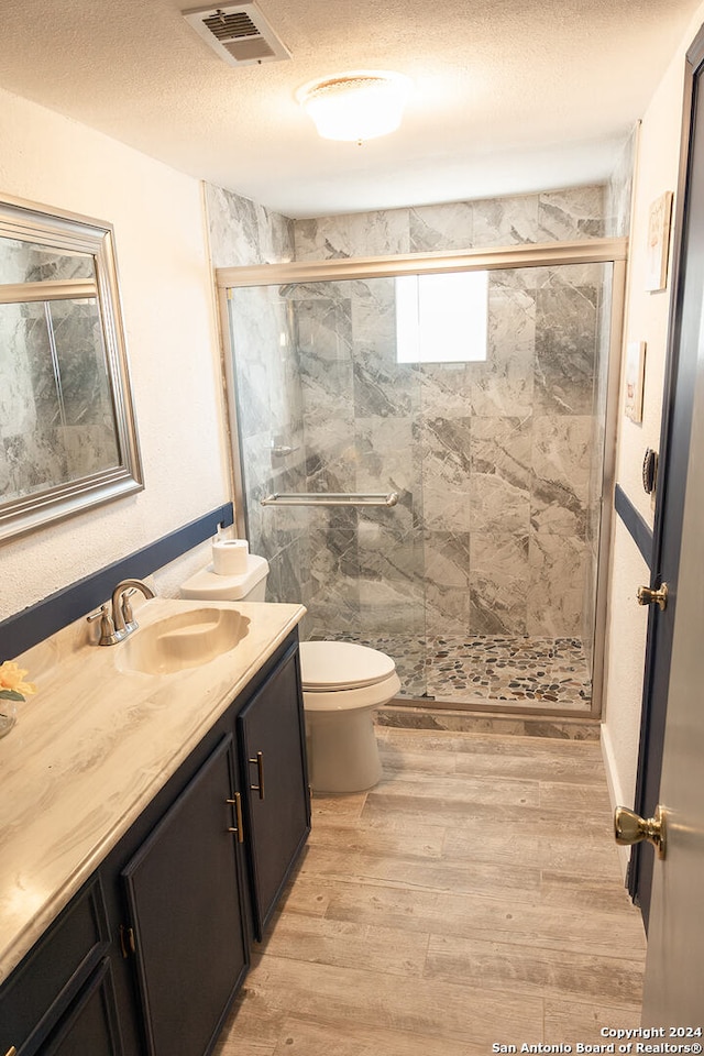 bathroom featuring walk in shower, hardwood / wood-style floors, vanity, and toilet