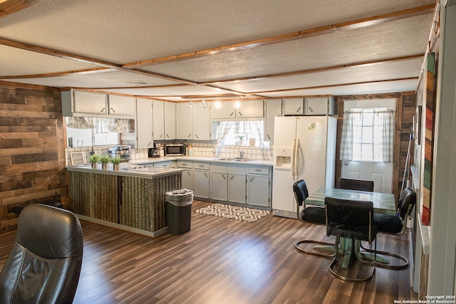 kitchen featuring white fridge with ice dispenser, wooden walls, dark wood-type flooring, and a healthy amount of sunlight