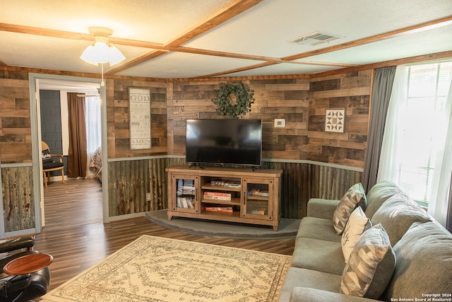 living room with ceiling fan, wooden walls, a wealth of natural light, and dark hardwood / wood-style flooring