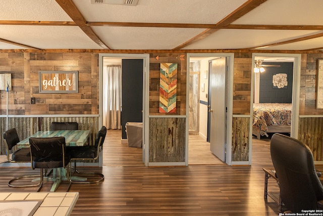 dining space featuring wood walls, hardwood / wood-style floors, and a textured ceiling