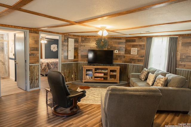 living room featuring ceiling fan, hardwood / wood-style flooring, wooden walls, and a textured ceiling