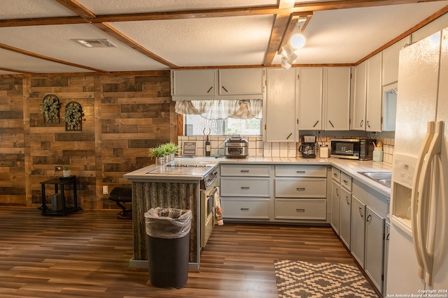 kitchen with wooden walls, decorative backsplash, dark hardwood / wood-style floors, white refrigerator with ice dispenser, and a textured ceiling