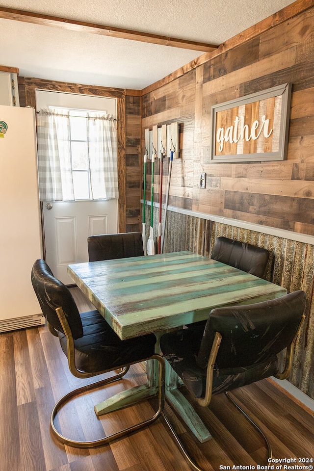 dining area featuring wooden walls, wood-type flooring, and a textured ceiling