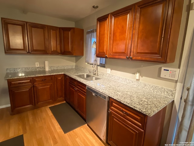 kitchen featuring sink, stainless steel dishwasher, light hardwood / wood-style floors, and light stone countertops