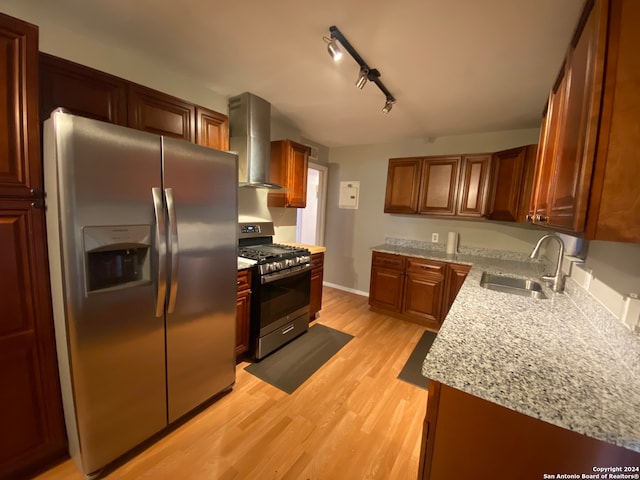 kitchen with rail lighting, wall chimney range hood, light hardwood / wood-style flooring, sink, and appliances with stainless steel finishes