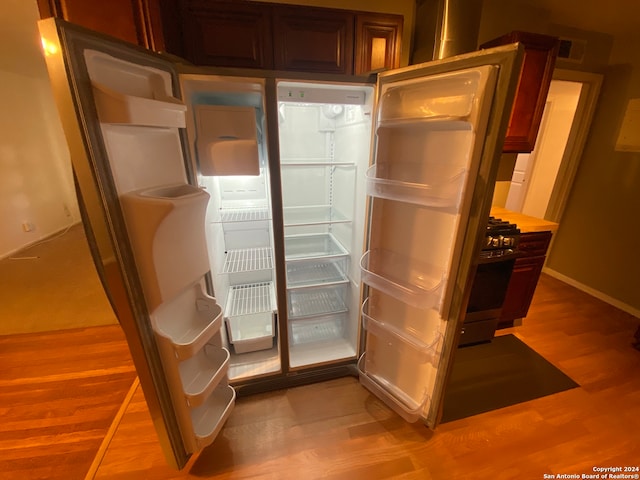 interior space featuring refrigerator with ice dispenser, light wood-type flooring, and black gas stove