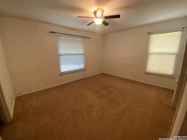 empty room with ceiling fan and light carpet