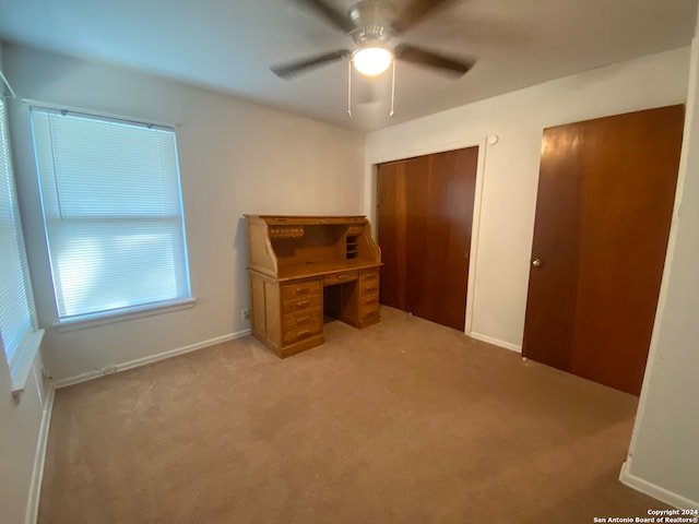 unfurnished office with ceiling fan and light carpet