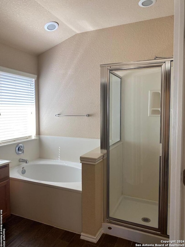 bathroom with plus walk in shower, wood-type flooring, a textured ceiling, lofted ceiling, and vanity