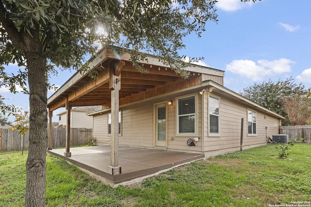 rear view of property with central AC unit, a patio area, and a yard