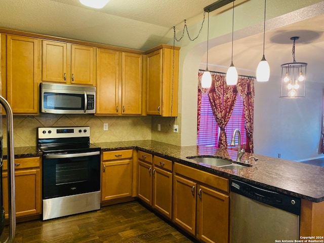 kitchen with kitchen peninsula, appliances with stainless steel finishes, dark hardwood / wood-style flooring, sink, and pendant lighting