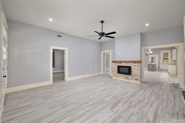 unfurnished living room with a fireplace, light hardwood / wood-style floors, and ceiling fan with notable chandelier