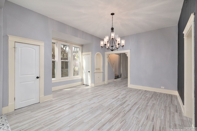 unfurnished dining area with an inviting chandelier and light hardwood / wood-style flooring