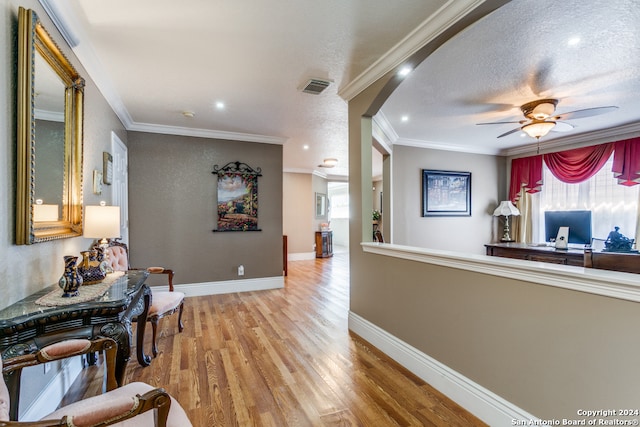 corridor with crown molding, light hardwood / wood-style flooring, and a textured ceiling