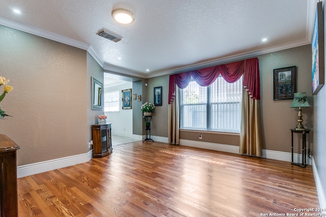 unfurnished living room featuring ornamental molding, wood-type flooring, and a textured ceiling