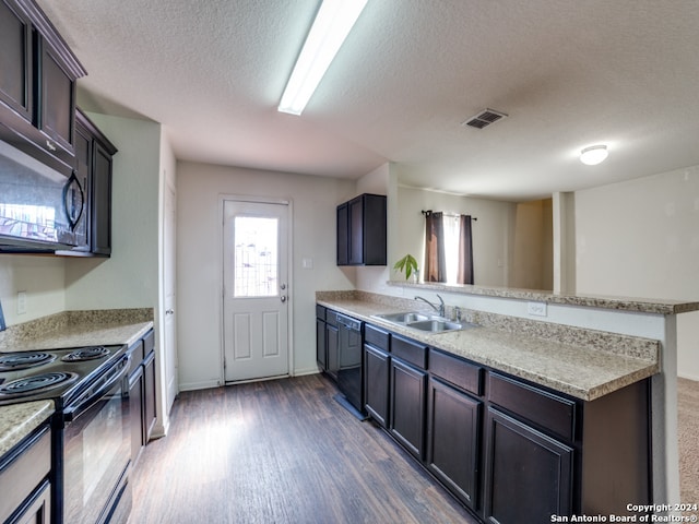 kitchen with sink, kitchen peninsula, a textured ceiling, dark wood-type flooring, and black appliances