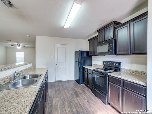 kitchen with ceiling fan, dark brown cabinetry, sink, black appliances, and dark hardwood / wood-style floors