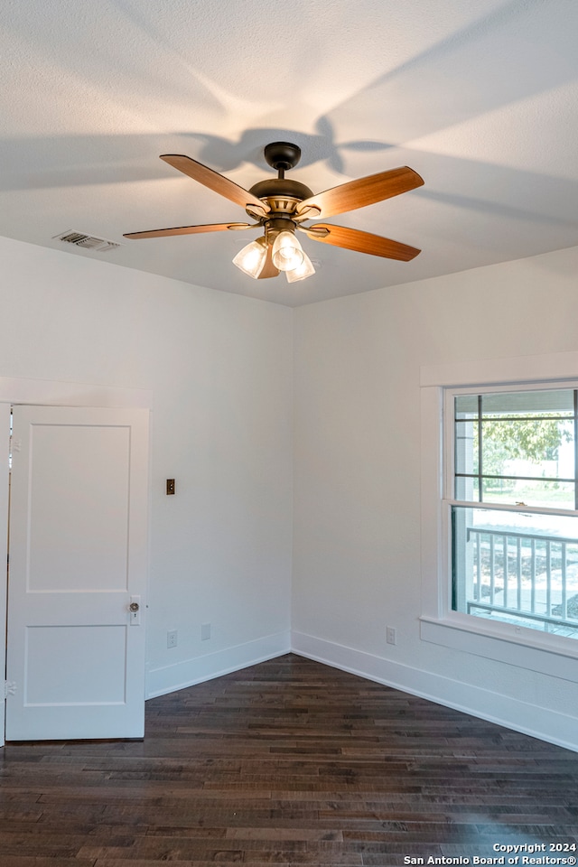 unfurnished room featuring dark wood-type flooring, a textured ceiling, and ceiling fan