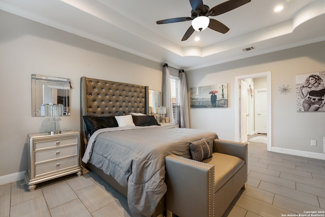 bedroom with ensuite bath, ceiling fan, and a tray ceiling