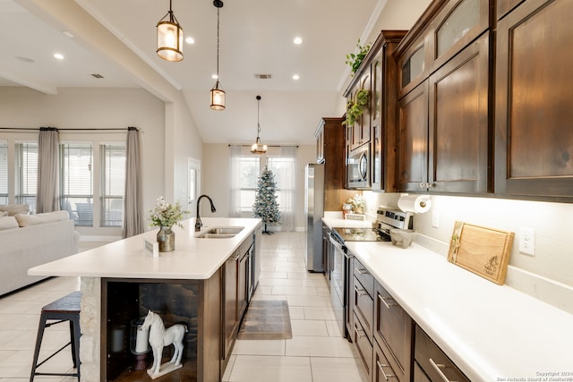 kitchen featuring light tile patterned floors, sink, a center island with sink, decorative light fixtures, and appliances with stainless steel finishes