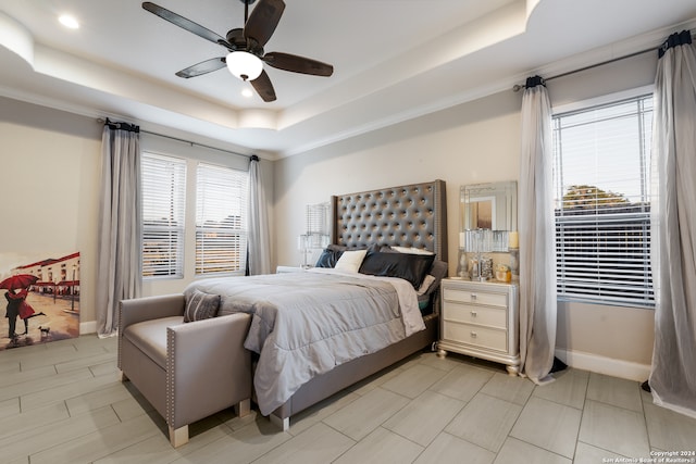 bedroom featuring ceiling fan, a raised ceiling, and multiple windows