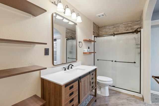 bathroom featuring vanity, hardwood / wood-style flooring, toilet, and a shower with door