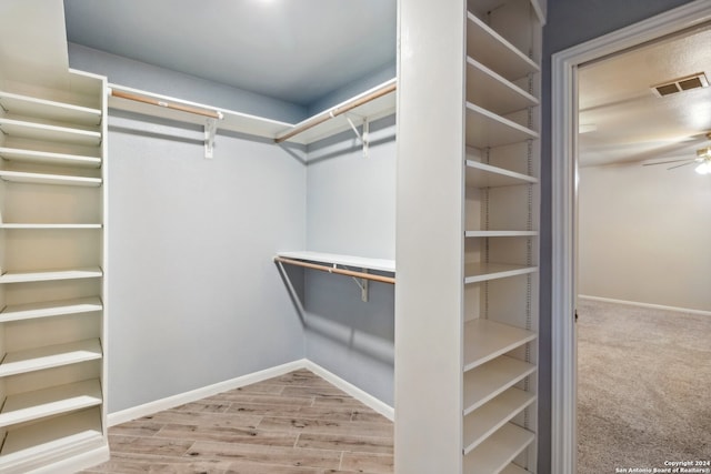 walk in closet featuring wood-type flooring and ceiling fan