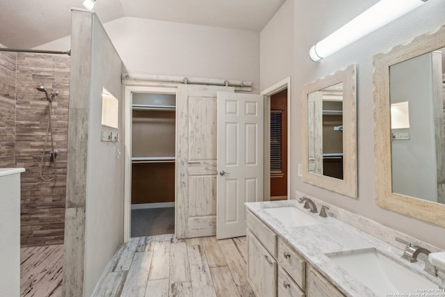 bathroom featuring tiled shower, vanity, lofted ceiling, and hardwood / wood-style flooring