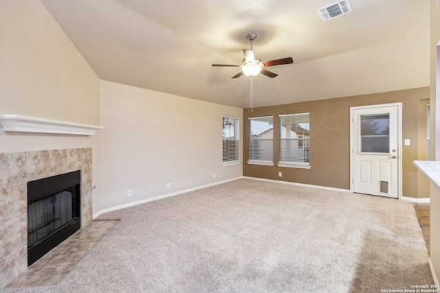 unfurnished living room with ceiling fan, lofted ceiling, a fireplace, and light carpet