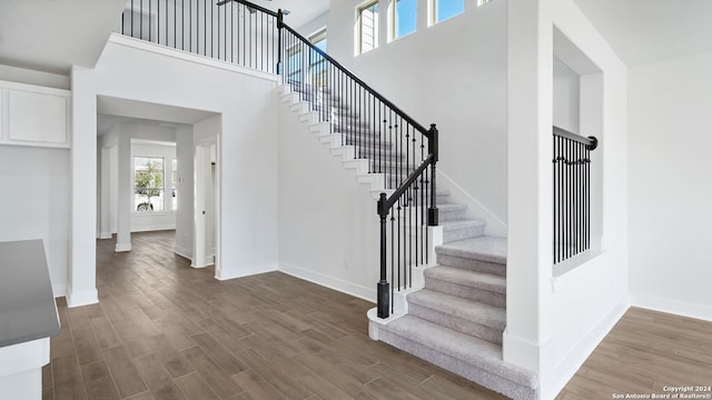 stairs with a towering ceiling and hardwood / wood-style floors