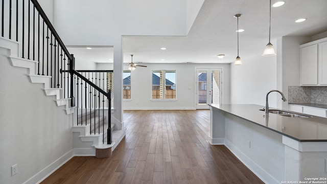 kitchen featuring sink, dark hardwood / wood-style flooring, pendant lighting, white cabinetry, and backsplash