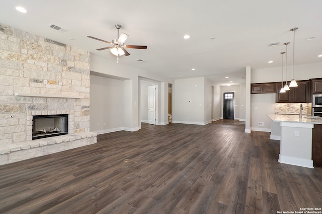 unfurnished living room with ceiling fan, a fireplace, and dark hardwood / wood-style floors