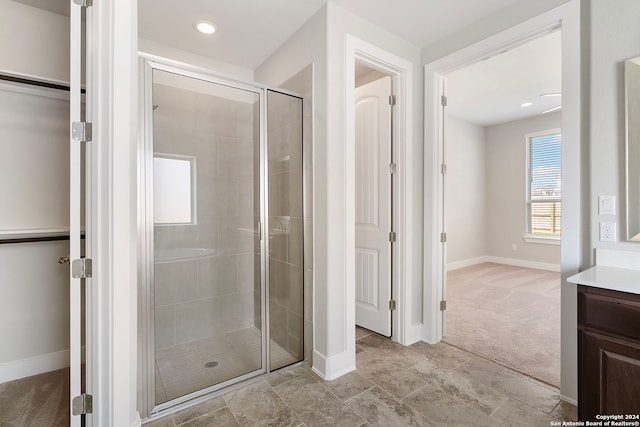 bathroom featuring a shower with door and vanity