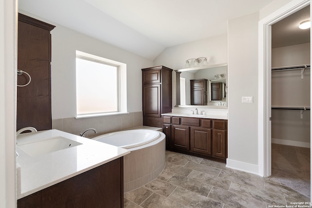 bathroom with vanity, vaulted ceiling, and a washtub