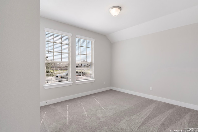 unfurnished room featuring lofted ceiling and carpet