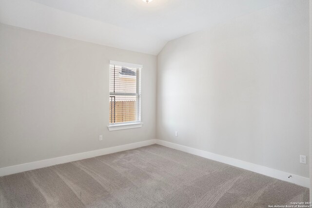 carpeted empty room with lofted ceiling