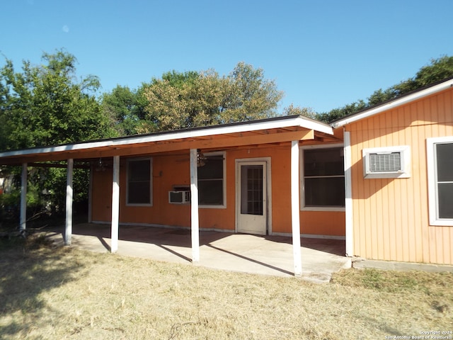 rear view of house with a carport, a wall mounted air conditioner, a lawn, and a patio area