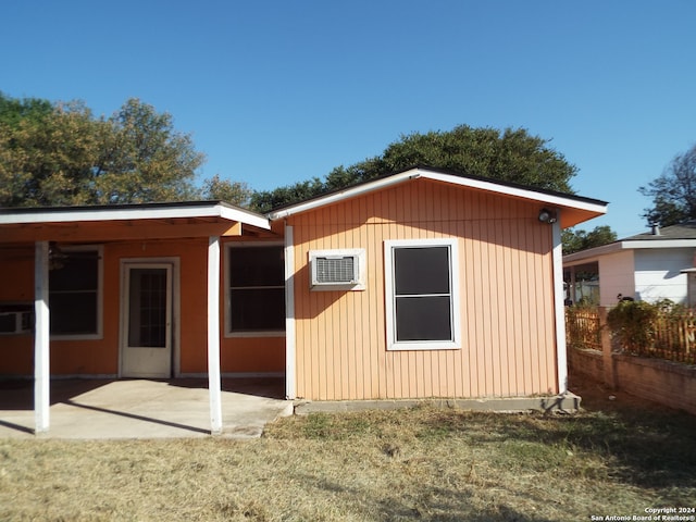 back of property with a yard, a patio, and a wall unit AC