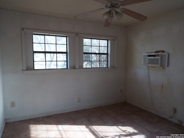 spare room featuring an AC wall unit, a healthy amount of sunlight, and ceiling fan