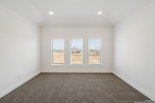 unfurnished room featuring lofted ceiling and dark colored carpet