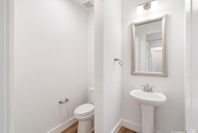 bathroom with wood-type flooring, sink, and toilet