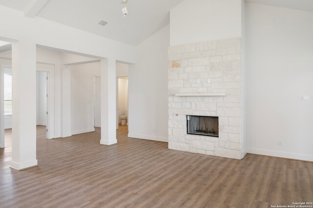 unfurnished living room featuring a fireplace, vaulted ceiling, and hardwood / wood-style floors