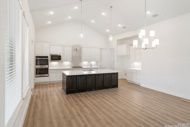 kitchen with a kitchen island with sink, appliances with stainless steel finishes, white cabinetry, and light hardwood / wood-style flooring