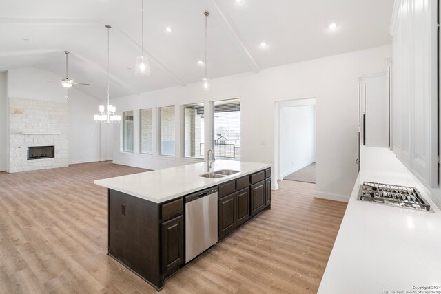 kitchen with a kitchen island with sink, sink, a fireplace, dark brown cabinets, and dishwasher