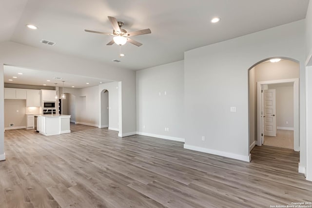 unfurnished living room featuring ceiling fan and light hardwood / wood-style floors