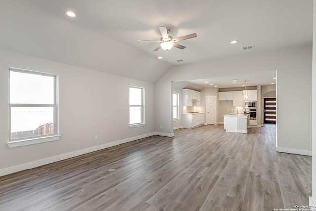 unfurnished living room with lofted ceiling, light hardwood / wood-style floors, and ceiling fan