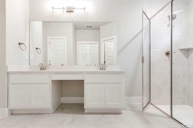 bathroom with a tile shower, vanity, and tile patterned floors