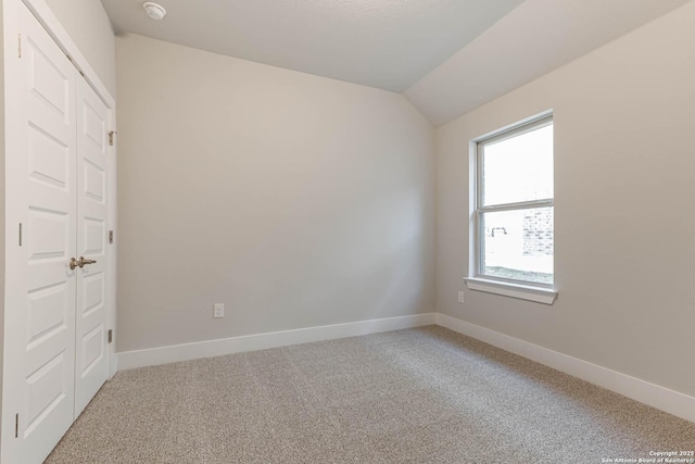 empty room with lofted ceiling and carpet floors