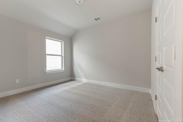 carpeted spare room with vaulted ceiling