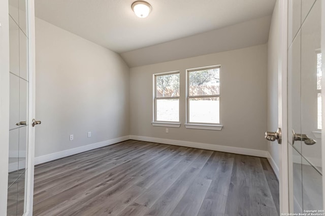 spare room with wood-type flooring and vaulted ceiling